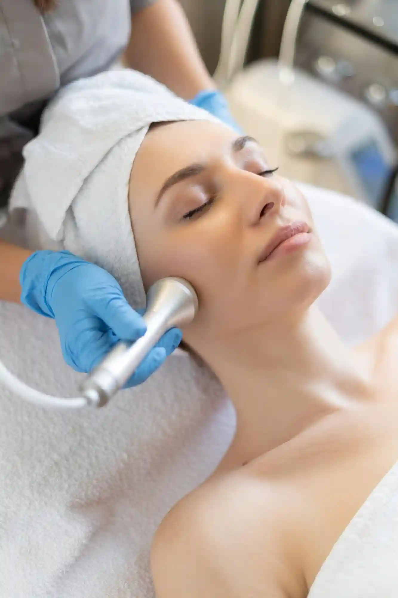 Woman receiving a facial treatment with a handheld device